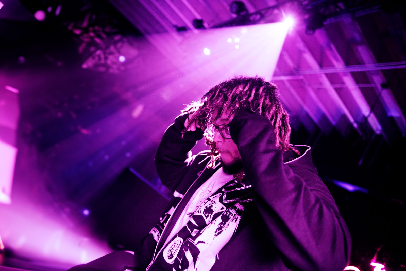 Artist performing under purple stage beams with a guitar