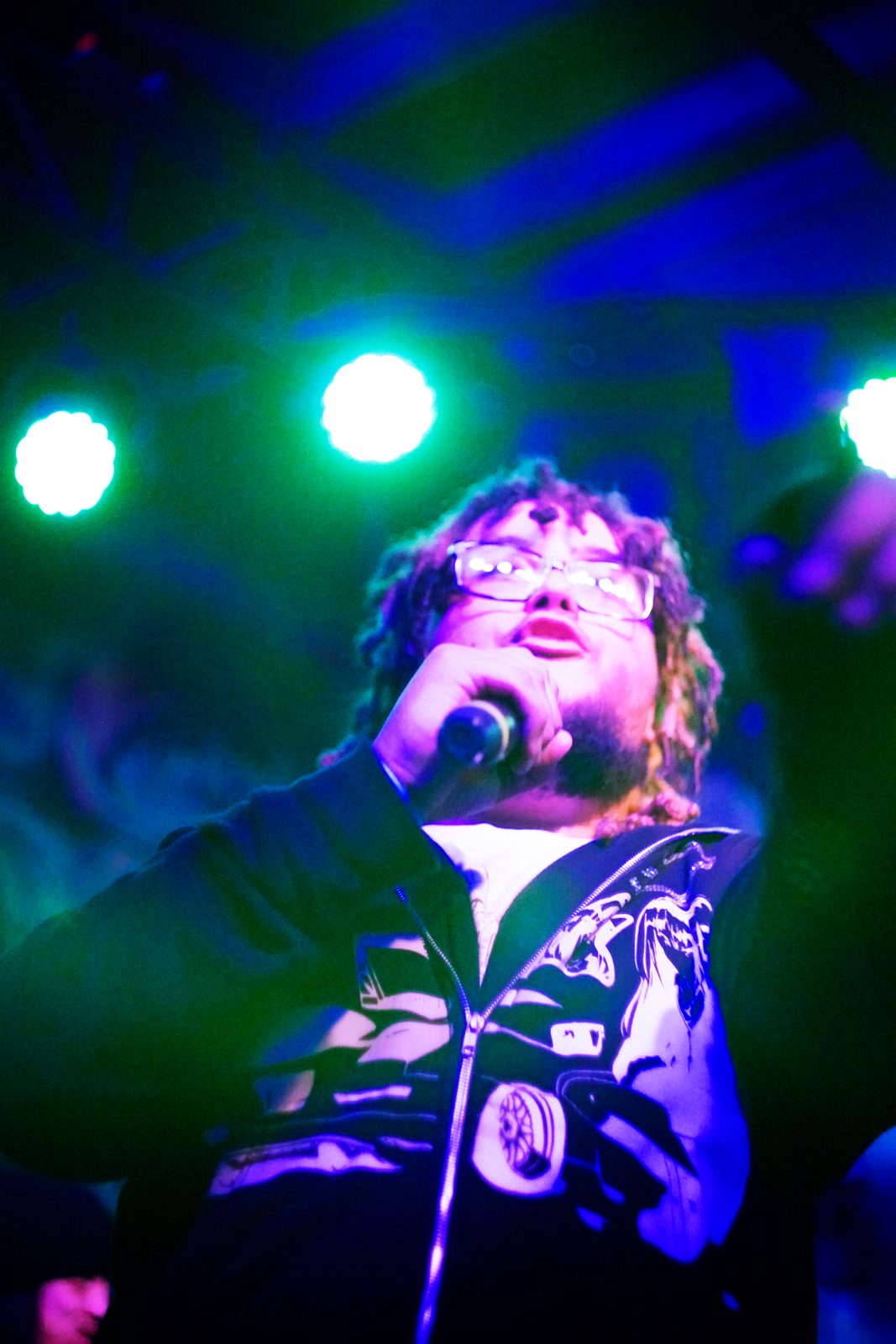 Rapper on the mic washed in green stage light