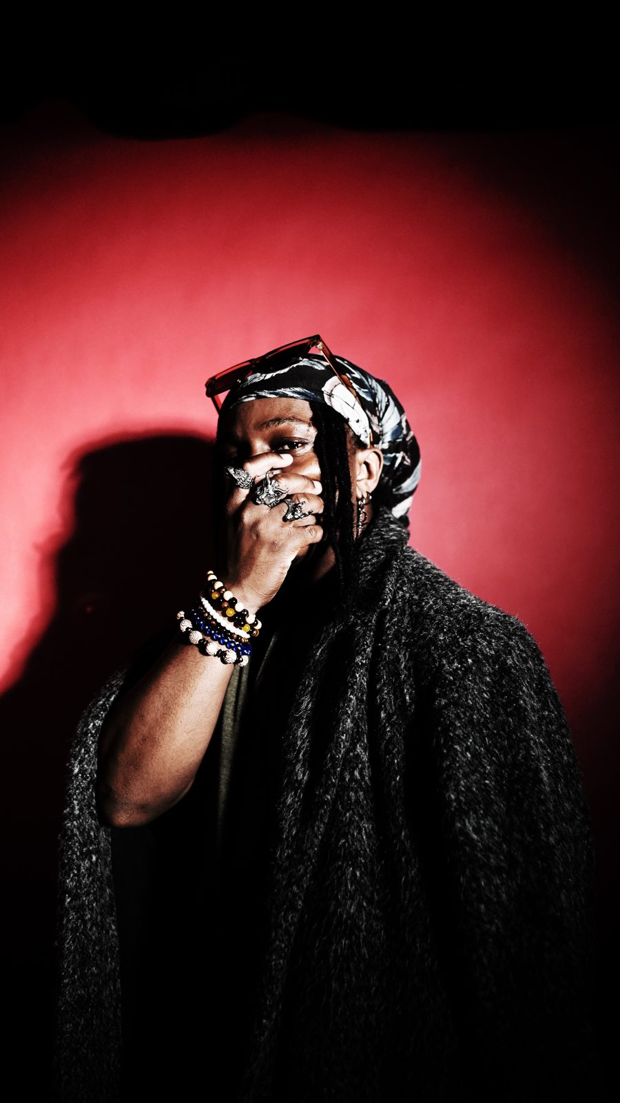 Portrait in a hood, hand raised, red wall behind
