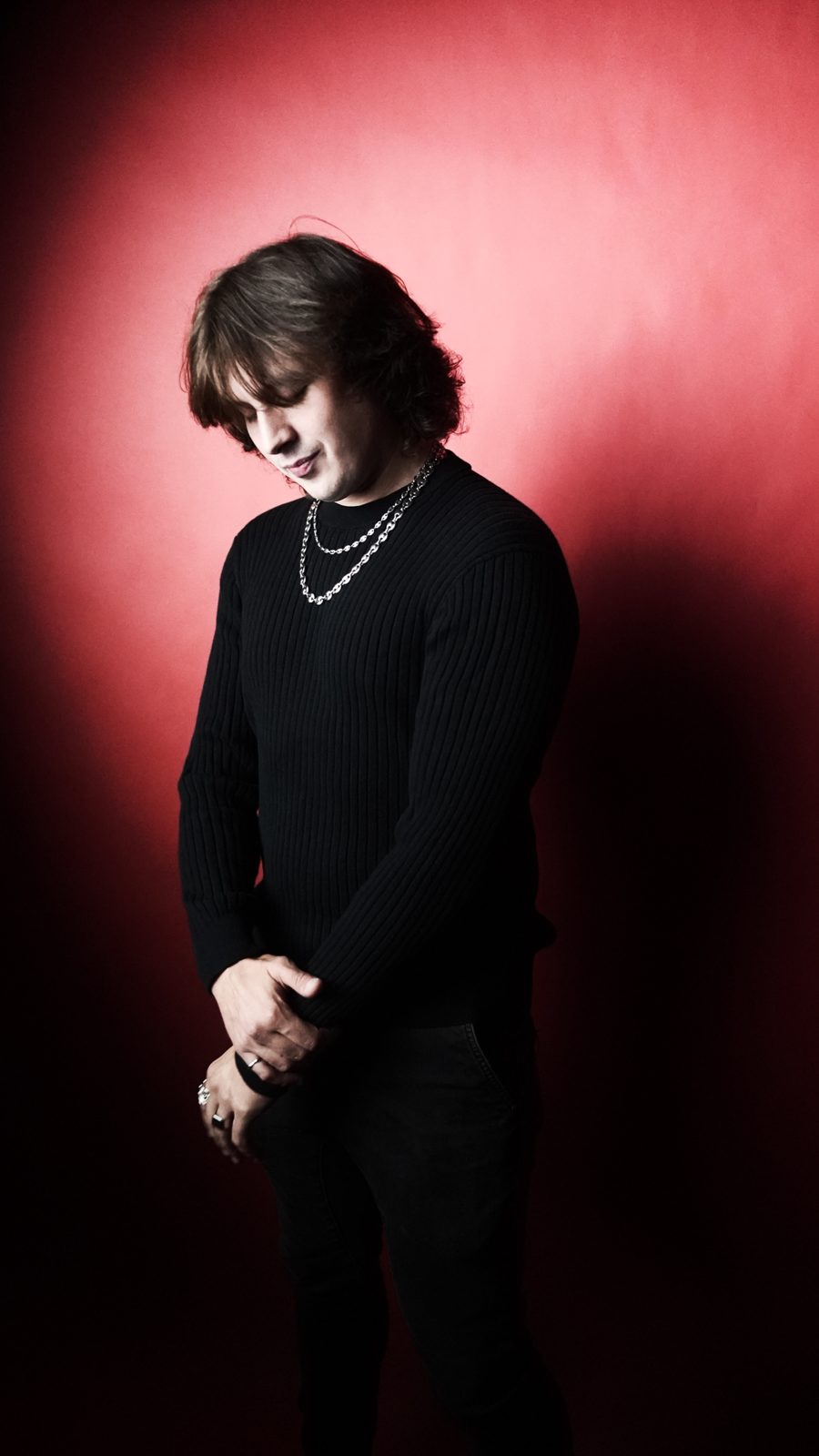Artist in all black against a red backdrop
